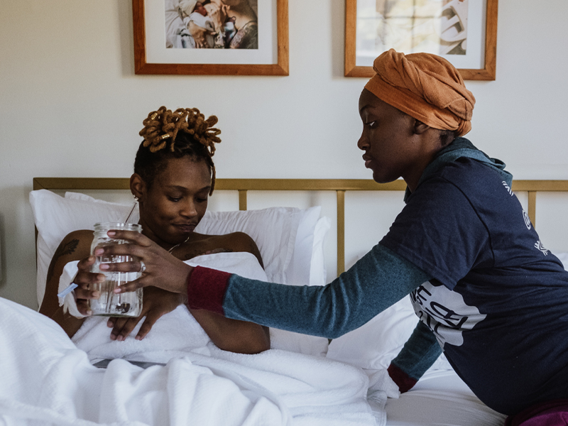 Birthing person holds infant while support person hands them water