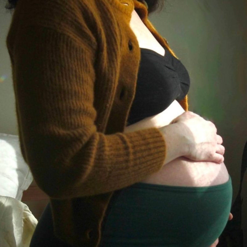 Pregnant person holds belly